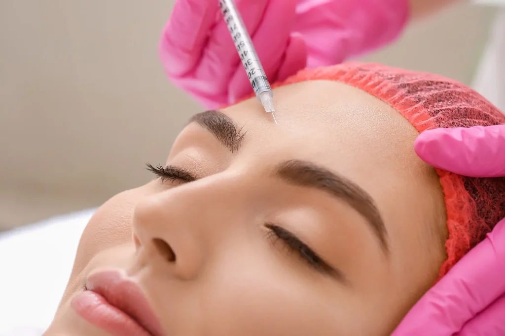 Esthetician injecting Botox in woman’s forehead