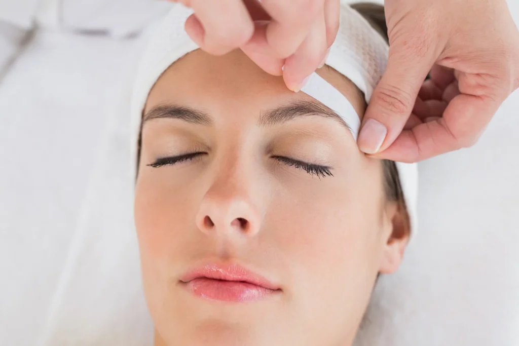 A young woman getting eyebrow waxing done