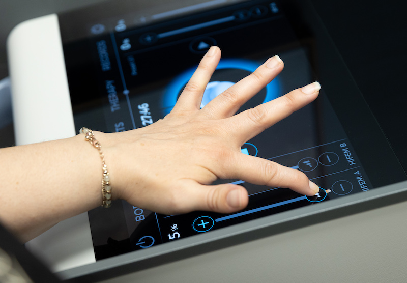 Closeup of Xanadu provider's hand operating the Emsella control board for pelvic floor therapy in Fort Collins