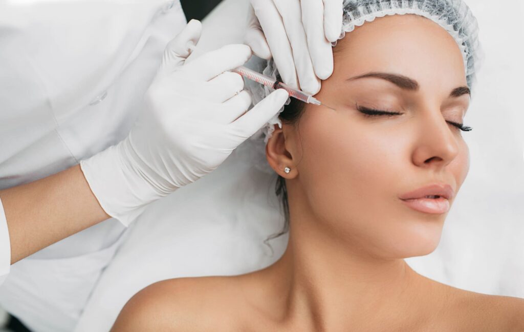 A woman receives a cosmetic injection near her eye from a professional